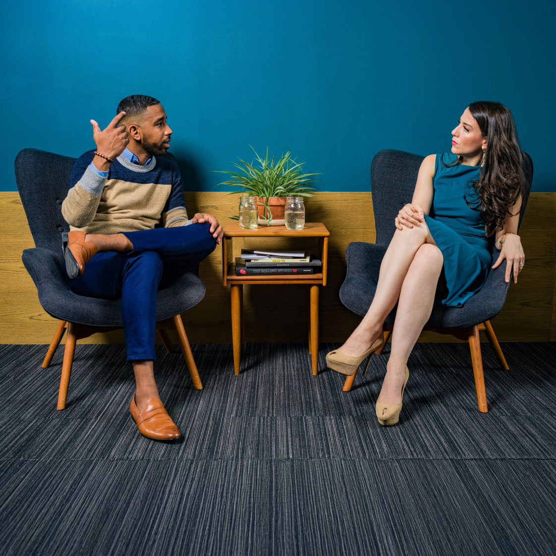 a man and women chatting in two chairs with a blue background